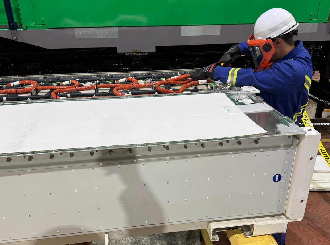 Technician wearing protective equipment while working on a battery assembly.