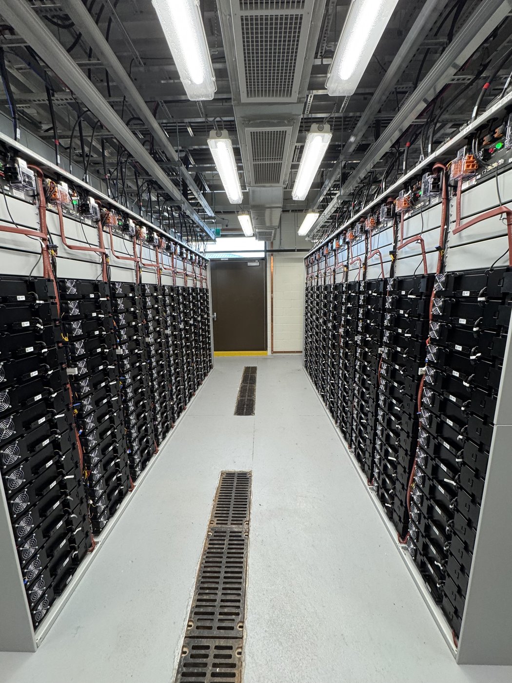 Battery racks arranged along a central access aisle.